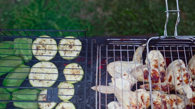 在花园里烧烤。烤鸡肉和蔬菜。摄像机在烤架上移动视频素材