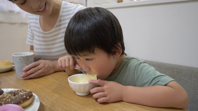 小儿子在饭厅吃冰淇淋，妈妈正坐在一起视频素材画面1