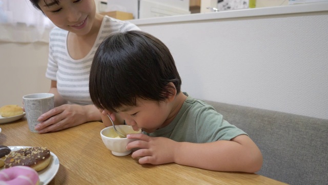 小儿子在饭厅吃冰淇淋，妈妈正坐在一起视频素材画面2