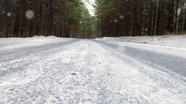 缓慢的运动。公路上的积雪覆盖的道路在一个冬天的森林。神秘的冬天森林。路很滑。危险的道路。冰雪覆盖的道路。视频素材