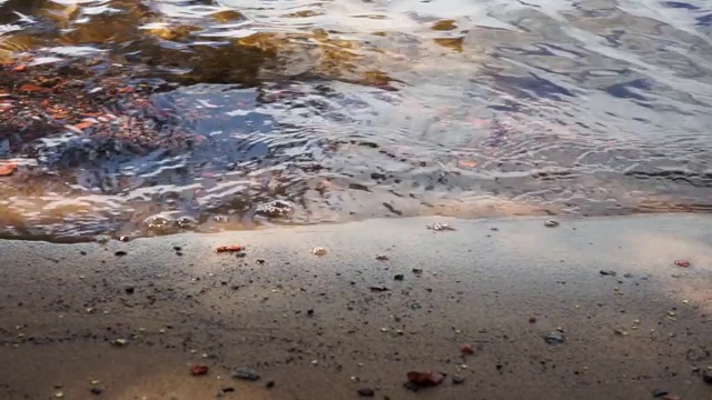 水面上的涟漪在沙滩上形成微弱的波浪视频素材