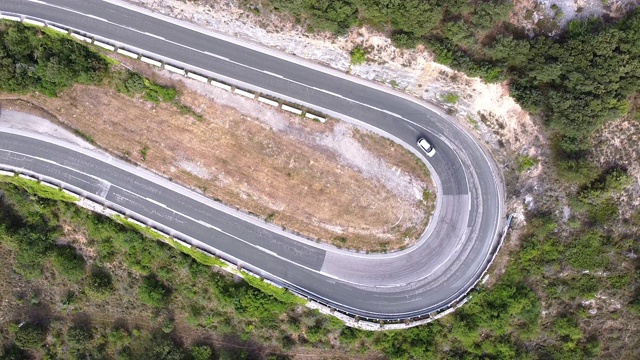 鸟瞰图蜿蜒的道路在高山口槽绿色松林。高质量的画面视频素材