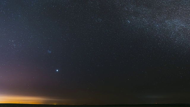 在早春的乡村田野景观上，夜晚星空与发光的星星。在银河系恒星之间的天空中行星金星的明亮辉光。夕阳下的天空。FullHD间隔拍摄视频素材