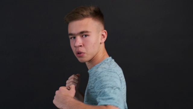 肖像集中的十几岁的男孩拳击他的手几乎在相机的特写在黑色的背景慢动作。拳击比赛。运动、培训、青年。青少年的生活方式。健康的生活方式视频素材画面4
