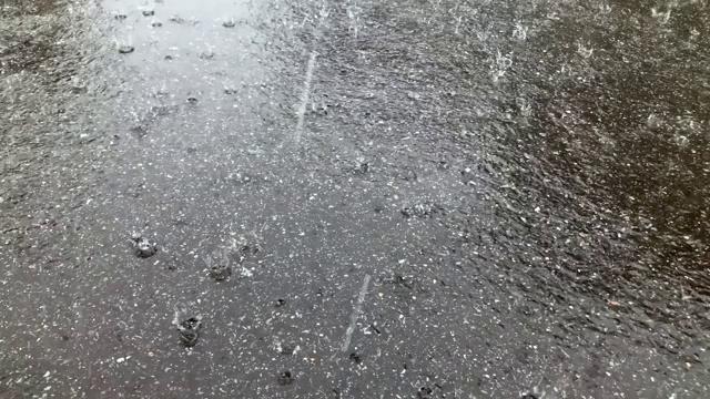 在雨天，很多雨滴打在沥青路面上。视频素材