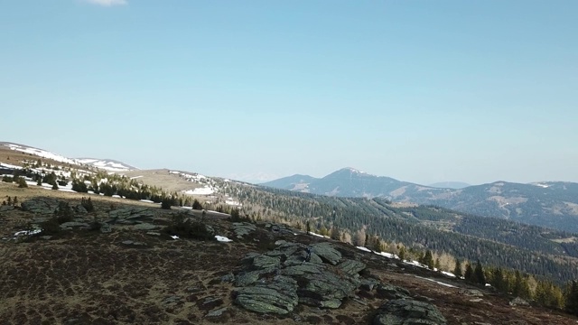 一架无人机在春季初捕捉到了奥地利阿尔卑斯山的景观。草地上部分覆盖着雪。高大的山脉环绕四周。发现了大自然。多石贫瘠的景观视频素材