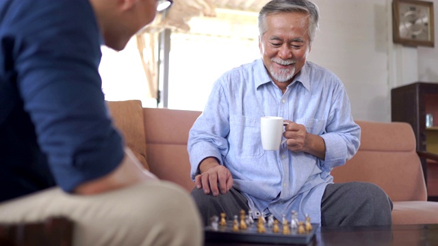 亚洲老人和儿子在家里下棋视频素材