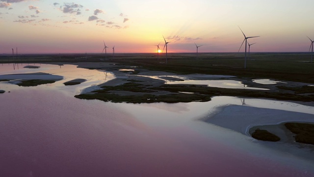 一个风电场的背景下，美丽的傍晚金色的夕阳。为绿色生态世界生产可再生能源。鸟瞰图。视频素材