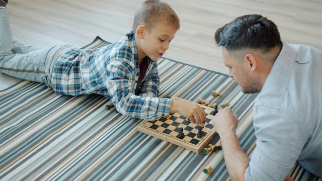 聪明的孩子下棋棋盘游戏与父亲花空闲时间在家视频素材