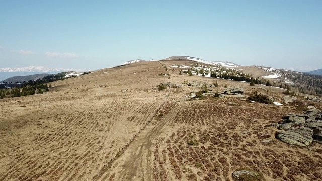 一架无人机在春季初捕捉到了奥地利阿尔卑斯山的景观。草地上部分覆盖着雪。高大的山脉环绕四周。发现了大自然。多石贫瘠的景观视频素材