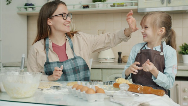 快乐的家庭妈妈和女儿烤饼干和在厨房表达爱的乐趣视频素材