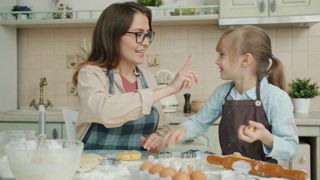 慢动作的年轻女士烹饪和有乐趣的可爱的小女儿在家里在厨房视频素材