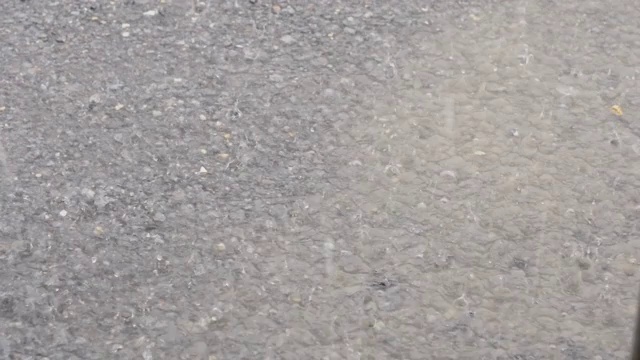 雨滴在水泥地板上，大雨溅湿了道路，雨点和路面，水在道路上流动，季节和天气，4k运动。视频素材