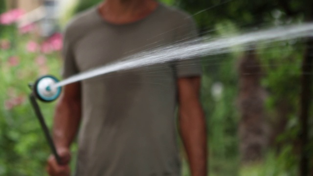 特写人物浇灌花园。有人在后院喷水。水灌溉视频素材