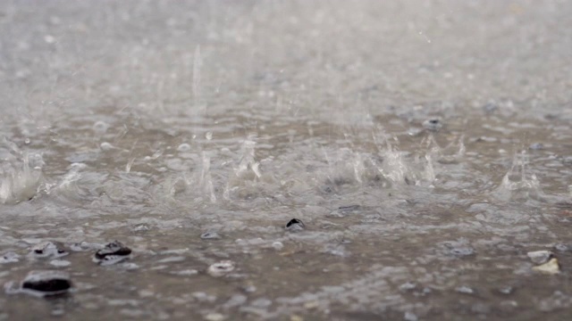 雨滴在水泥地板上，大雨溅湿了道路，雨点和路面，水在道路上流动，季节和天气，4k运动。视频素材