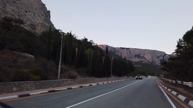 在一个温暖的夏夜，道路的傍晚风景穿过山脉视频素材