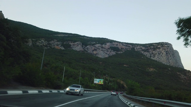 在一个温暖的夏夜，道路的傍晚风景穿过山脉视频素材