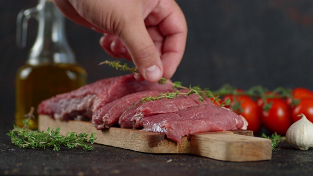 男子的手把百里香放在生牛肉片上。视频素材