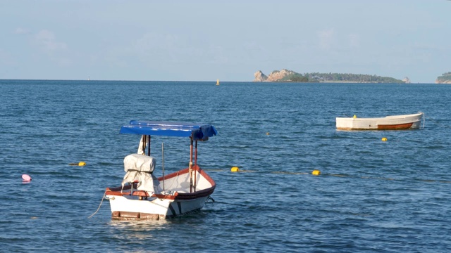 小型木制渔船漂浮在海岸附近的蓝色海水上视频素材