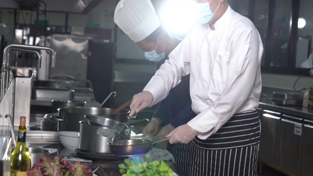 在酒店餐厅厨房里准备食物的厨师团队。视频素材画面2