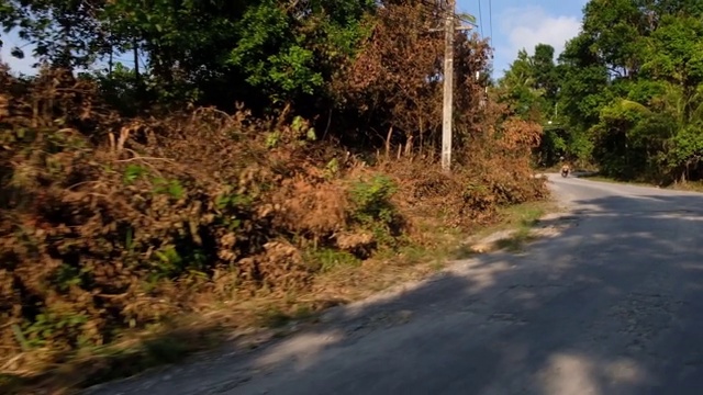 沿着空旷的乡村公路，穿过阳光明媚的泰国苏梅岛，沿着风景优美的热带天堂岛进行田园诗般的公路旅行视频素材