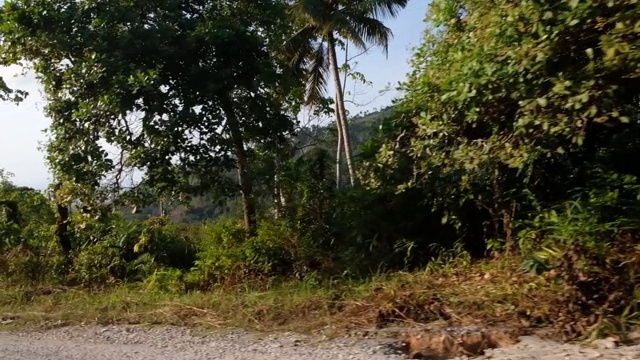 沿着空旷的乡村公路，穿过阳光明媚的泰国苏梅岛，沿着风景优美的热带天堂岛进行田园诗般的公路旅行视频素材