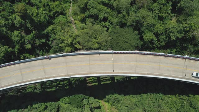 无人机拍摄的汽车驾驶穿过穿越热带雨林的桥梁道路的鸟瞰图视频素材