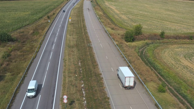 载货拖车在笔直的道路上行驶并运送货物的卡车鸟瞰图。摄像机跟踪在乡村公路上行驶的运送卡车。飞过农村的交通。慢动作视频素材