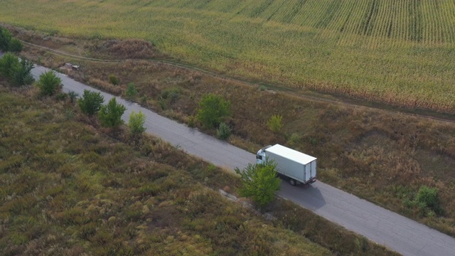 航拍的卡车与货物拖车驾驶在道路上运输货物。在乡村田野附近的高速公路上行驶的运货车。自然风景的观点。物流的概念。视频素材画面1