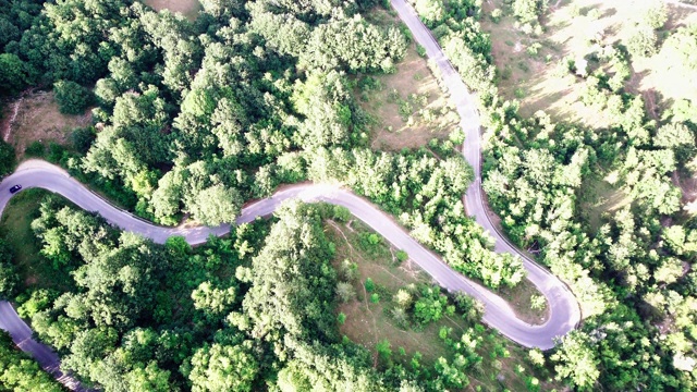 镜头B:无人机在蜿蜒曲折的道路上空盘旋。无人机4K视频，夏日阳光明媚的山路上蜿蜒视频素材