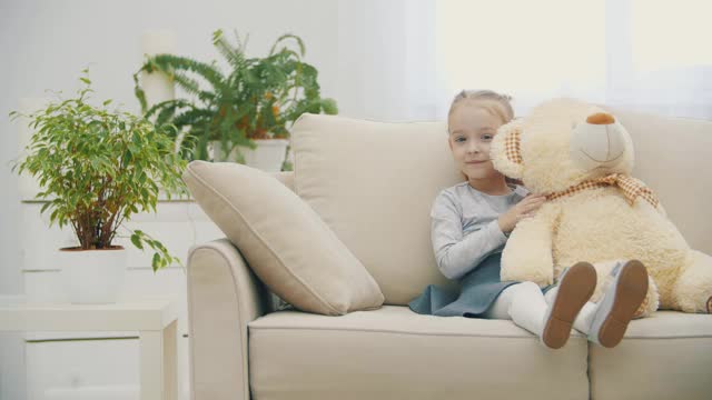 可爱的小女孩和她的泰迪熊分享秘密和微笑的4k视频。可爱女儿的概念。视频素材