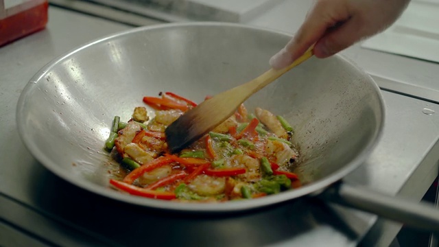 在煎锅里烤新鲜蔬菜和虾，然后搅拌。视频素材