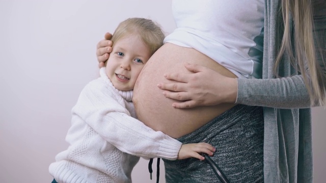 小孩儿抱着怀孕的妈妈，小肚子在白墙上视频素材