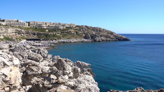 地中海，海岸，多岩石的海岸，一个阳光明媚的日子，海湾是酒店与游客的人，罗德岛的希腊。视频素材