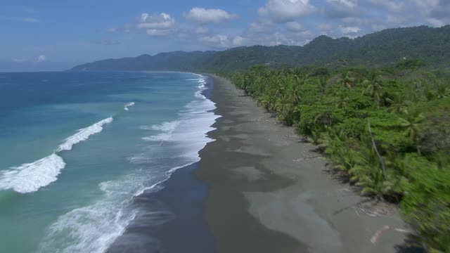 海浪撞击海滩的航拍与Peje Perrito泻湖在蓬塔雷纳斯，哥斯达黎加。视频素材