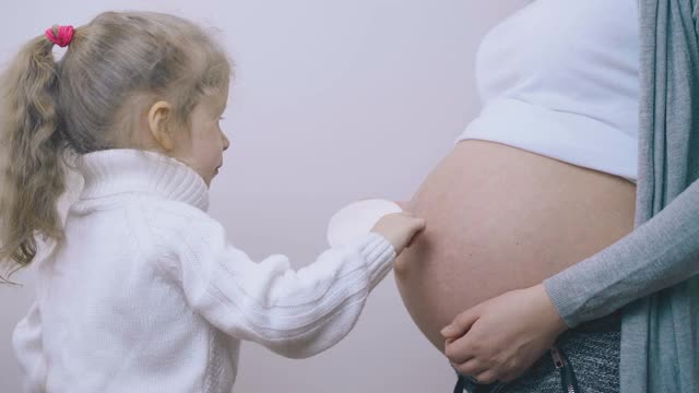 小女孩帮孕妇在肚子上涂霜视频素材