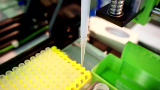 自动分析仪机械手移动一个装满明亮液体的塑料烧瓶。特写镜头视频素材画面3