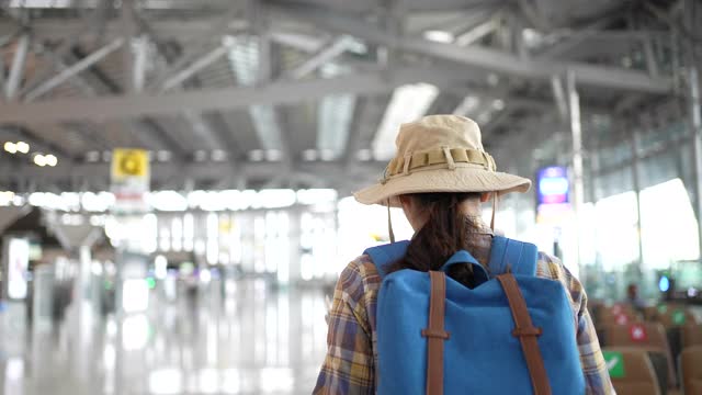 年轻的亚洲女子走在候机楼的登机口，慢镜头视频素材