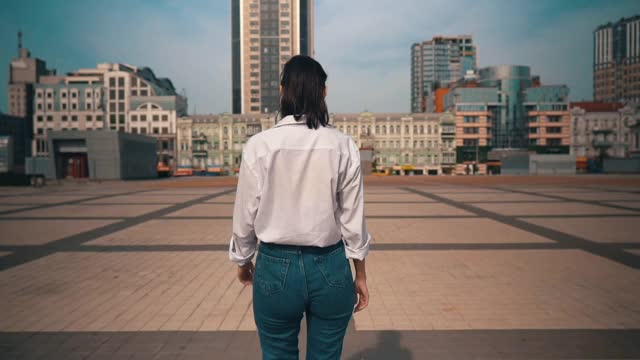 背景，一个穿着休闲装走在城市里的女人转向镜头视频素材