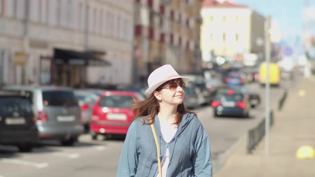 快乐的女人戴着帽子走在城市里，女人在城市里旅行视频素材