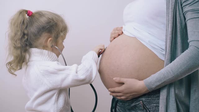 女孩在怀孕妈妈肚子里听宝宝的心跳视频素材