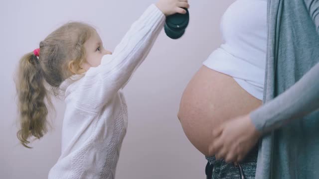 小女孩把耳机戴在孕妇肚子里视频素材