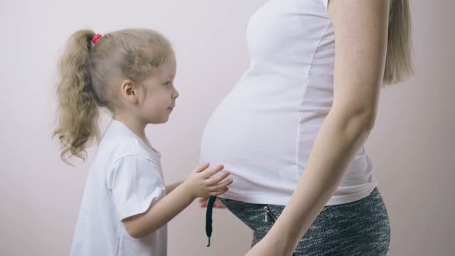 漂亮女孩在家抱着大肚子的怀孕妈妈视频素材