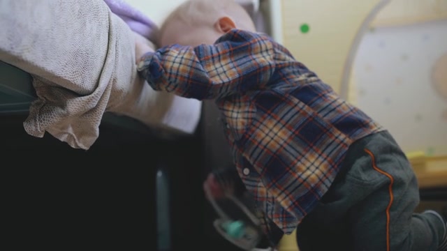 滑稽的孩子歪歪扭扭地倚靠在软床上的木地板上视频素材画面3