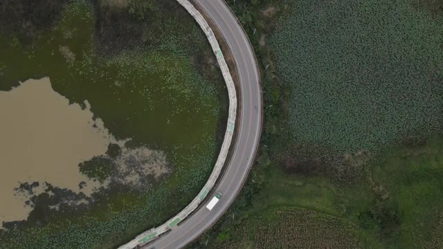 4k空中俯视图缩小汽车、卡车和摩托车在湿地、湖泊和农田的环形道路和自行车道上行驶视频素材