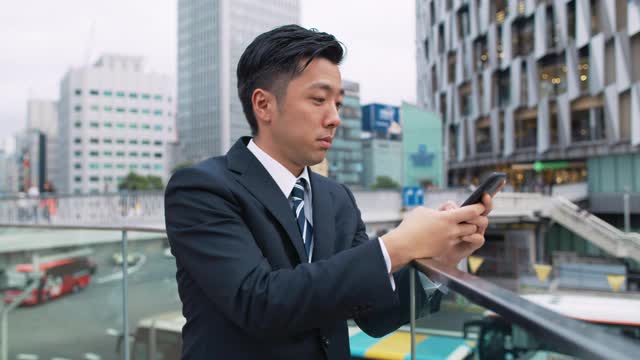 一个日本商人在城市里打手机视频素材