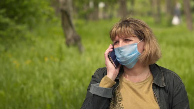 一个戴医用口罩的女人正在打电话。视频素材