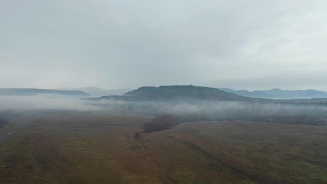 4k鸟瞰图飞过桌子岩石和山脉的背景雾视频素材