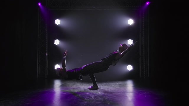 两个男子体操杂技演员摆一个平衡姿势。在团队合作中表演复杂戏法的强壮运动员的剪影。在聚光灯下的黑色背景上。慢动作视频素材画面2