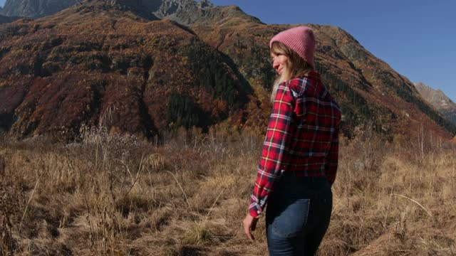 年轻女子享受在秋天的山。高山快乐游客视频素材